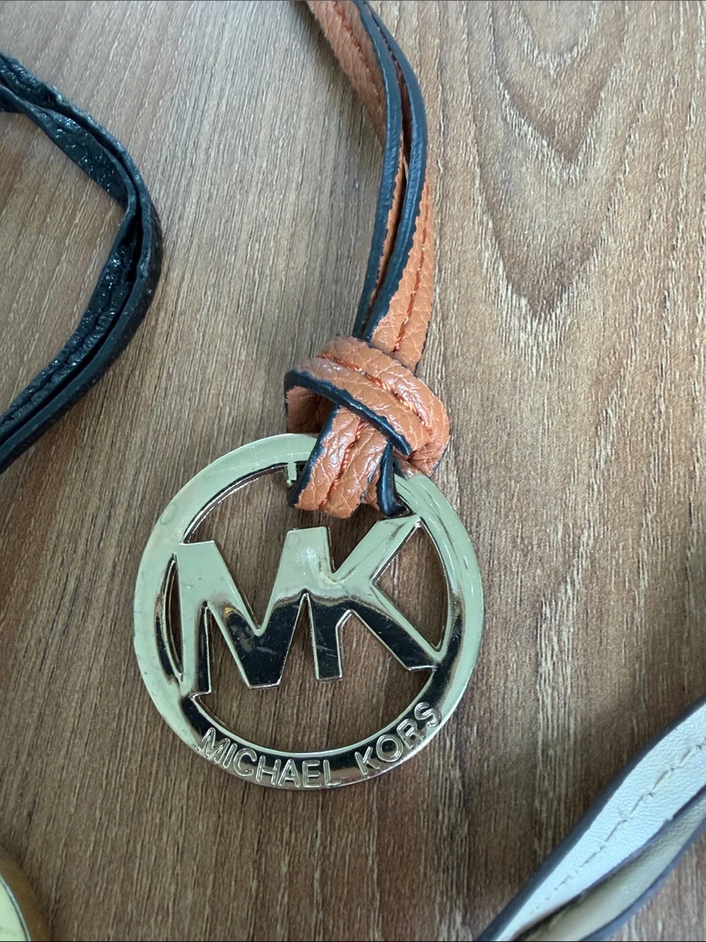 Set of four Michael Kors MK logo handbag charms featuring large round gold-tone